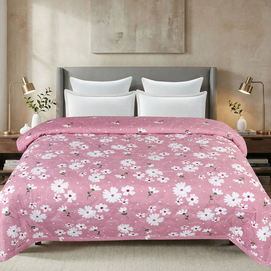 Bed with pink floral comforter and white pillows in a bedroom setting.